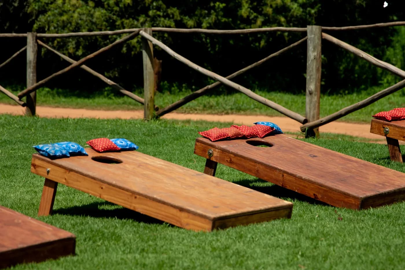 Wooden cornhole boards with red and blue bags on the grass